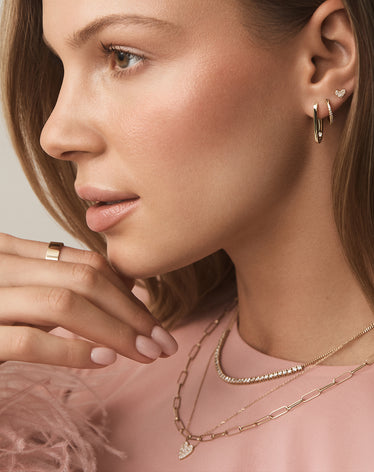 woman in stacked 14k gold diamond earrings and necklaces