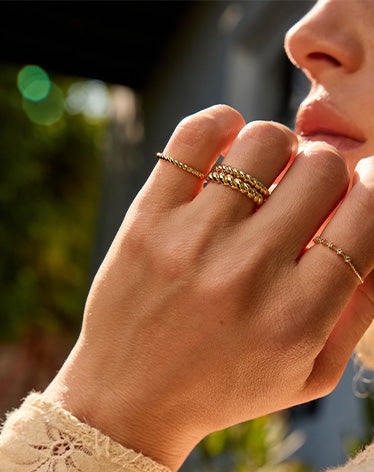 womans fingers stacked in gold rings